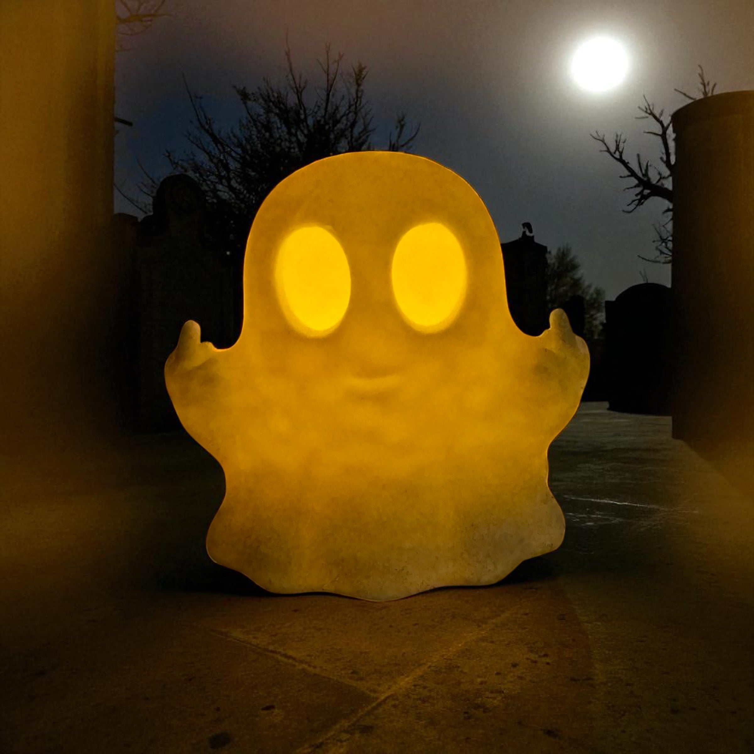 Ghost-shaped lamp glowing in the dark with a full moon in the background